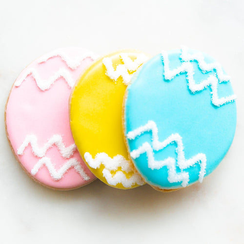 blue, yellow, light pink iced easter cookies outside of bag